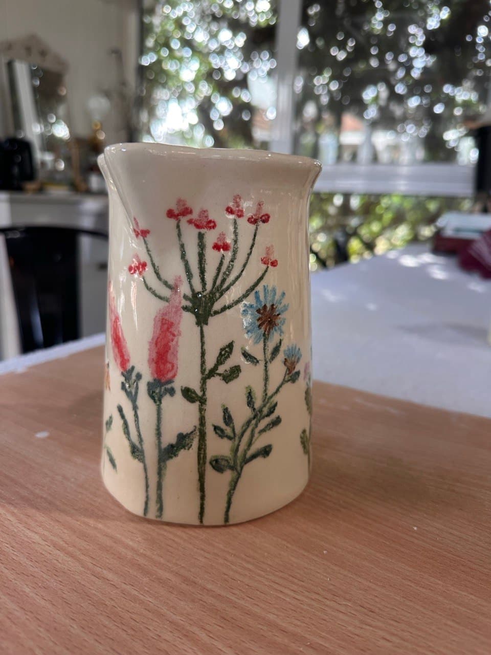 La Jarra Silvestre sobre una mesa de madera, con ventanales y luz de jardín de fondo