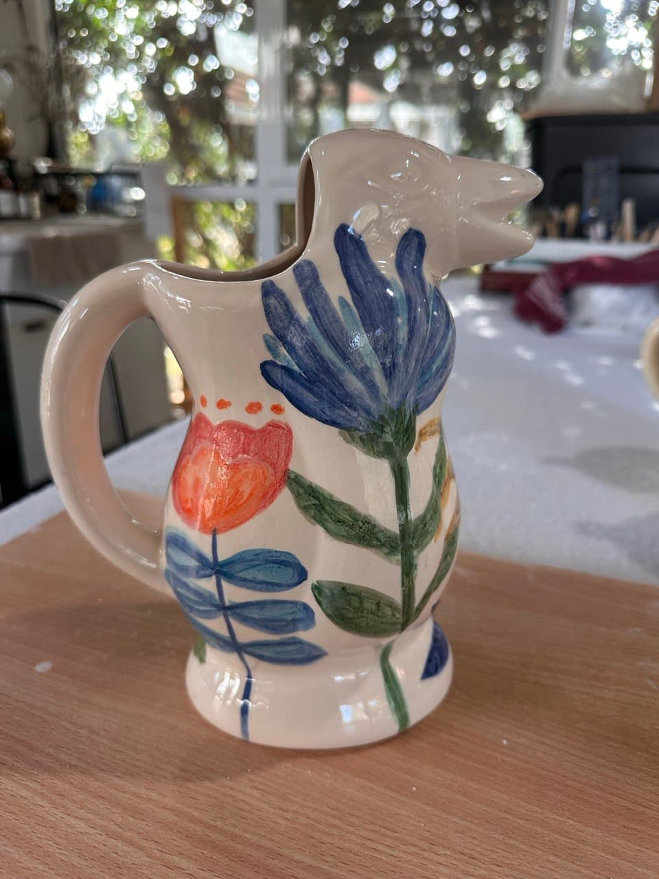 La Jarra Flora sobre una mesa de madera en la cocina de Cali, con plantas y luz de jardín de fondo