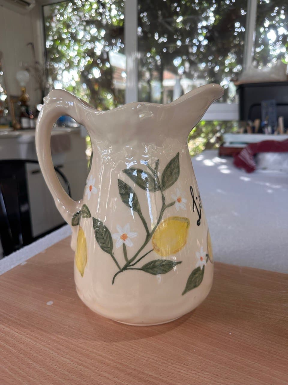 La Jarra Limonare sobre una mesa de madera, con ventanales y luz de jardín de fondo