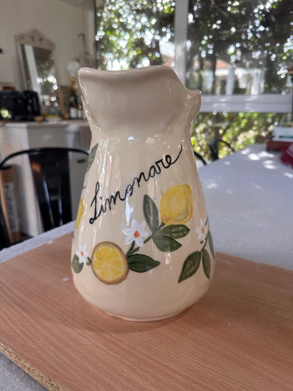 El otro lado de la Jarra Limonare, con la palabra Limonare escrita en cursiva negra entre limones amarillos, hojas verdes y azahares