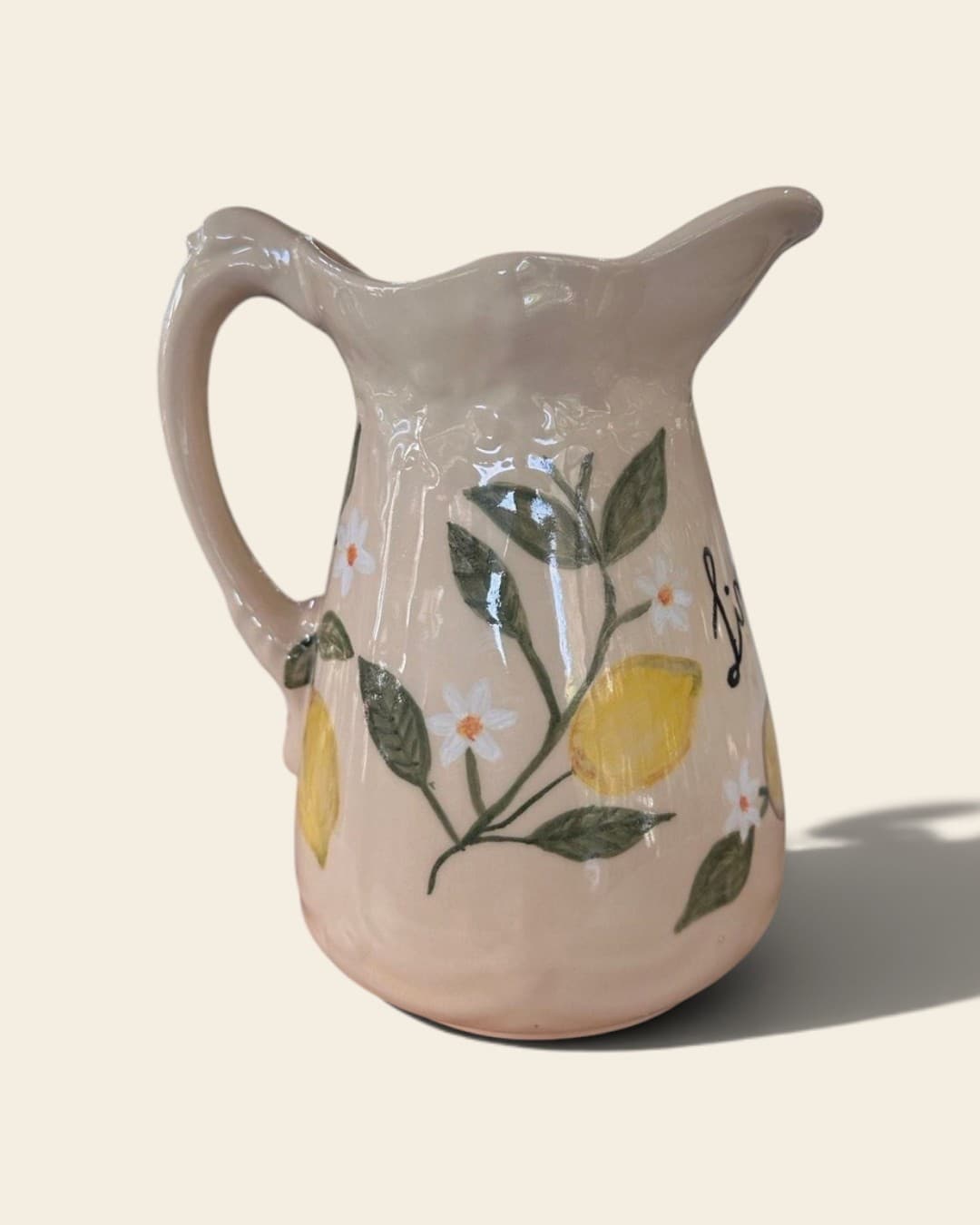 Jarra de cerámica color manteca con borde ondulado, limones amarillos en relieve, hojas verdes y flores de azahar pintadas a mano; de costado asoma la palabra Limonare escrita en cursiva
